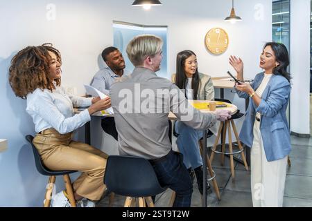Professionnels des affaires s’engageant dans des discussions animées et partageant des idées lors d’une réunion productive dans un bureau de coworking moderne Banque D'Images