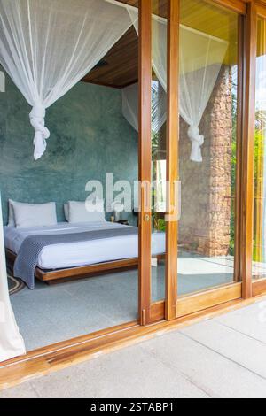 Chambre d'hôtel de luxe avec moustiquaire et porte ouverte. Intérieur confortable d'un hôtel tropical. Design de chambre confortable et élégant. Vacances en Afrique Banque D'Images