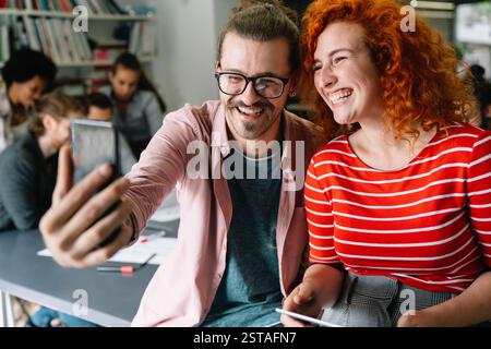 Sympathique collègue multiethnique heureux homme et femme s'amusant avec smartphone, travaillant ensemble Banque D'Images