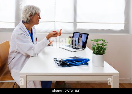 Médecin adulte consultant un jeune patient par appel vidéo sur ordinateur portable Banque D'Images