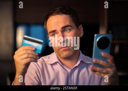Concept de paiement en ligne. L'homme en utilisant des cartes de crédit avec un téléphone mobile à fond blanc. Male hands holding Smartphone avec écran vide et banque de marche arrière Banque D'Images