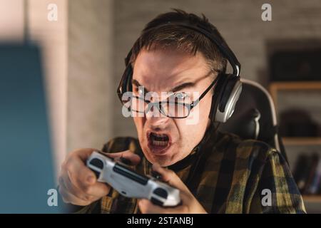 Gros plan sur la main d'un jeune homme jouant à des jeux. Attrayant beau joueur d'homme de sport se sentant heureux et joyeux, appréciant l'utilisation de la console de jeu joystick dans le Banque D'Images