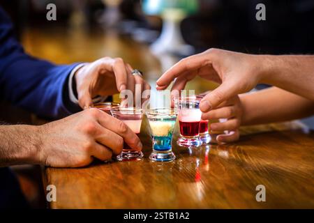 Plusieurs verres à alcool. Tirs sur un comptoir de bar. Ensemble de cocktails. Les mains masculines applaudissent avec des verres de vodka et de liqueur. Meilleurs amis Banque D'Images