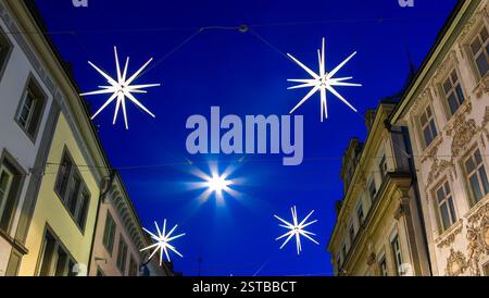 Une rue magnifiquement décorée de Noël de Sankt Gallen en Suisse avec des lumières en forme d'étoile suspendues entre les bâtiments contre une soirée bleu foncé Banque D'Images