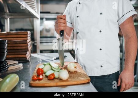 L'homme fait de la salade. Chef professionnel préparant la nourriture dans la cuisine. Banque D'Images