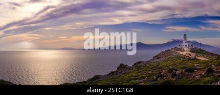 Grand plan du phare sur une colline proéminente donnant sur la baie de Mykonos avec le soleil couchant et les nuages spectaculaires Banque D'Images