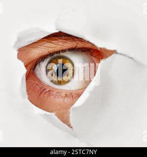 Oeil regarde à travers un trou dans le papier - espion Banque D'Images