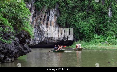 Les gens sur un bateau flottant sur une rivière entourée de forêts tropicales luxuriantes et de montagnes. Situé à Tam Coc Ninh Binh Vietnam Banque D'Images