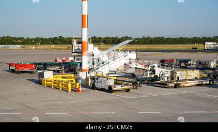 Parking pour véhicules sur le tarmac à l'aéroport de Duesseldorf. Vue sur les chariots à bande transporteuse de bagages, les véhicules d'escalier et les remorques de transport de bagages Banque D'Images