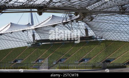 Stade olympique de Munich avec sa construction emblématique de toit de tente et des rangées vertes de sièges en été. Vue intérieure des rangées de sièges et du toit de la tente Banque D'Images