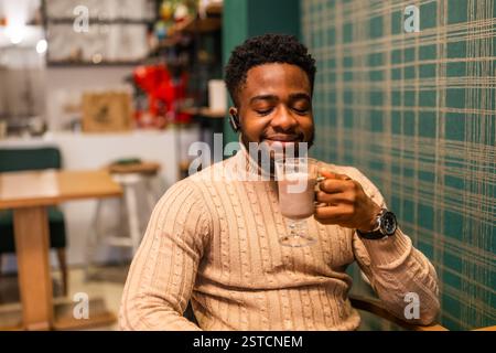 Jeune homme noir appréciant le chocolat chaud dans la barre. Portrait de l'homme qui boit du chocolat chaud. Banque D'Images