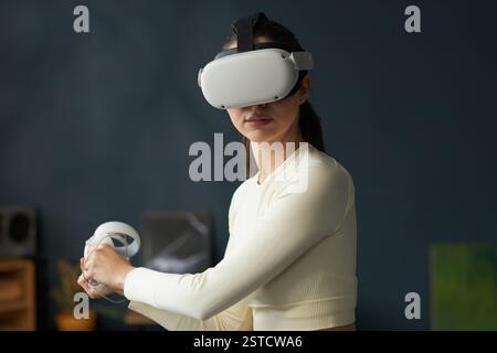 Femme portant un casque de réalité virtuelle et utilisant des contrôleurs Banque D'Images