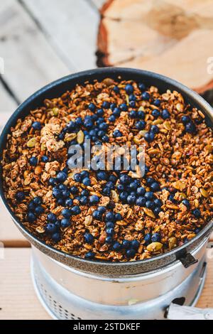 Un délicieux feu de camp : granola chaud avec des bleuets fraîchement cueillis, cuits sur un poêle Trangia au cœur de la nature. Banque D'Images