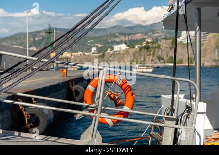 Sorrente, Italie - 26 mai 2024 : une bouée de sauvetage accrochée à un quai au port de Sorrente, avec les eaux calmes de la mer Méditerranée en arrière-plan. Banque D'Images