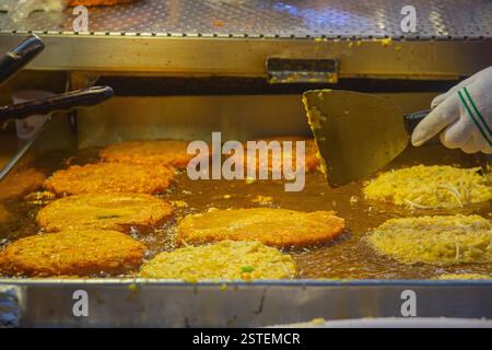 Bindae-tteok ou pancakes aux haricots mungo cuisant sur une plaque de cuisson recouverte d'huile au marché de Gwangjang à Séoul, en Corée. Marché de Gwangjang, un célèbre marché local. Banque D'Images