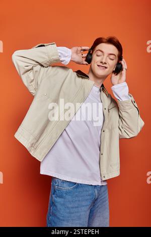 Un jeune homme beau écoute joyeusement de la musique avec des écouteurs, perdu dans l'instant présent. Banque D'Images