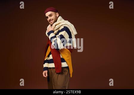 Un jeune homme modèle une tenue tendance avec un bonnet élégant et des tricots d'hiver superposés. Banque D'Images