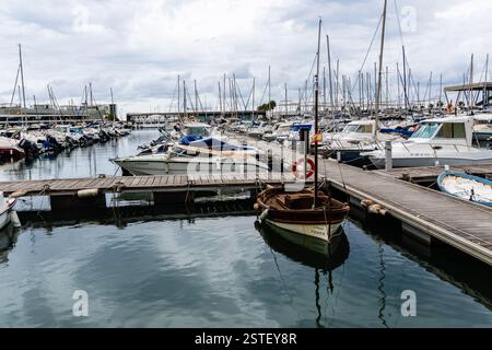 Denia, Espagne - 21 septembre 2024 : de nombreux bateaux sont amarrés dans une marina par temps nuageux. Un petit bateau en bois est au premier plan. Banque D'Images