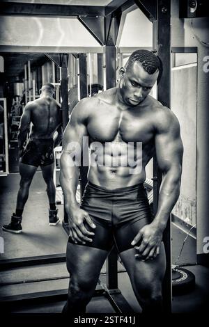 Beau bodybuilder masculin noir se reposant après l'entraînement dans la salle de gym Banque D'Images