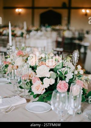 Les roses vibrantes et la verdure créent un magnifique arrangement floral sur la table pour la célébration du mariage. Banque D'Images