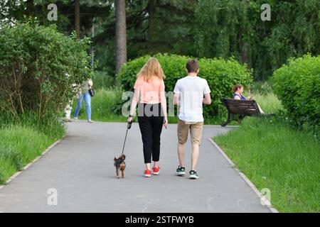 Moscou, Russie - 16 juin 2020. Deux adolescents marchent le Yorkshire terrier en laisse dans le parc Banque D'Images