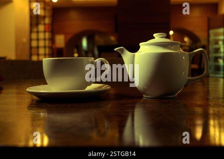 L'heure du thé. Thé blanc et théière sur la table en bois dans la chambre sombre, vue de côté Banque D'Images