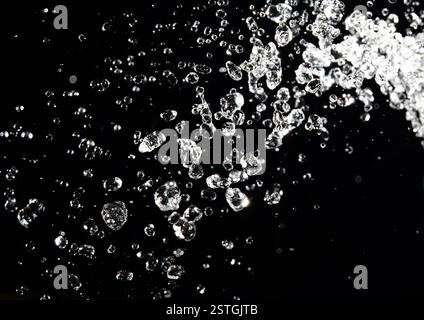 Éclaboussure d'eau isolée sur fond noir. les gouttes lévitent dans l'obscurité de l'air Banque D'Images