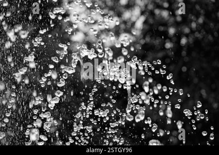 Gouttes d'eau voler dans le ciel sur fond noir focus sélectif. Les éclaboussures d'eau dans une goutte d'eau sombre battant Banque D'Images