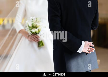 La mariée et le marié sont debout l'un à côté de l'autre. L'homme porte un costume noir et la femme porte une robe blanche Banque D'Images