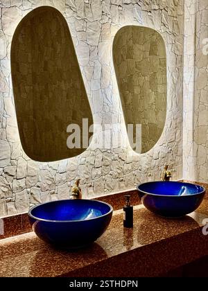 Design moderne de salle de bains avec lavabos en céramique bleue et miroirs rétro-éclairés photo élégante de deux lavabos en céramique bleue avec robinets dorés, placés sur un s poli Banque D'Images