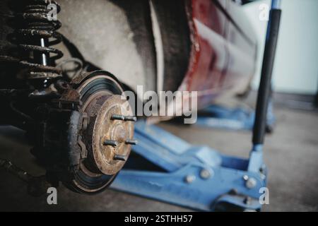 Gros plan d'une roue de voiture et d'un système de suspension sur un ascenseur hydraulique Banque D'Images