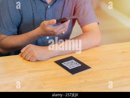 Homme scannant le code à barres qr code dans un restaurant ou un café. Paiement par code QR, portefeuille E , concept de technologie sans espèces. Banque D'Images
