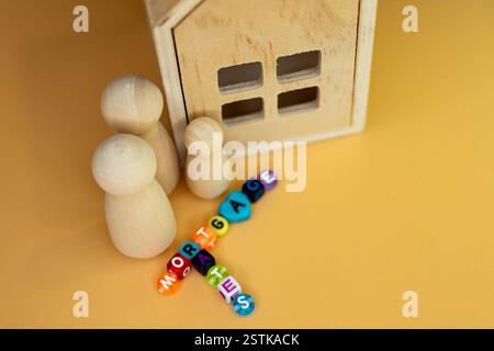 Figurines en bois ressemblant à une famille à côté d'un petit modèle de maison en bois, taux hypothécaires en perles colorées Banque D'Images