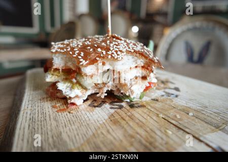 Hamburger mordant en gros plan sur une table en bois. Banque D'Images