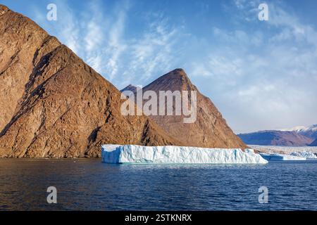 Iceberg géant, glacier et montagnes de roches rouges du parc national du nord-est du Groenland. Paysage de fjord d'été avec fond de ciel bleu. Banque D'Images