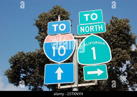 Panneaux routiers californiens bleus et verts indiquant l'Interstate 10 et la Californie du Nord 1. Une scène d'autoroute américaine classique avec des arbres Banque D'Images