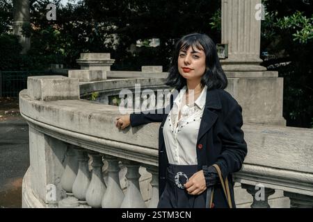 Femme hispanique élégante posant dans un cadre de parc urbain classique, mettant en valeur l'élégance et la confiance Banque D'Images