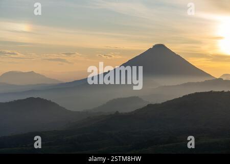 Un lever de soleil à couper le souffle sur une route de montagne sinueuse, entourée de vallées brumeuses et d'un ciel doré. Parfait pour les voyages, l'aventure et les thèmes de la nature. Banque D'Images