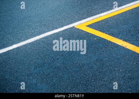 Surface asphaltée avec des lignes blanches et jaunes Banque D'Images