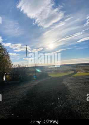 La photo capture un paysage serein sous un vaste ciel, mettant en valeur une scène tranquille avec un chemin sinueux et une végétation luxuriante Banque D'Images