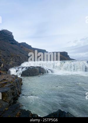 La photo capture un paysage naturel magnifique avec une cascade en cascade au-dessus d'un rebord rocheux dans un plan d'eau serein en contrebas Banque D'Images