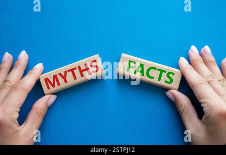 Symbole faits ou mythes. Concept mot faits ou mythes sur des blocs de bois. Main d'homme d'affaires. Beau fond bleu. Business and Facts or Myths concept. Banque D'Images
