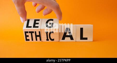 Symbole éthique et juridique. Homme d'affaires tourne à la main des cubes en bois et change le mot éthique à juridique. Beau fond orange. Affaires et éthique an Banque D'Images