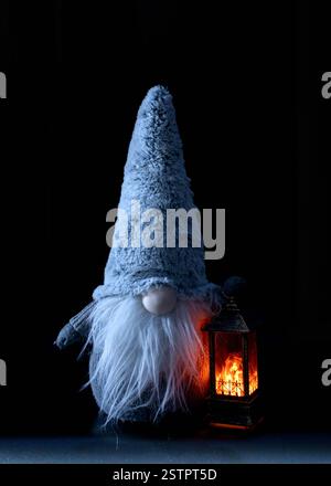 Nain avec une lanterne éclairée sur un fond sombre, avec un grand chapeau et une longue barbe blanche Banque D'Images