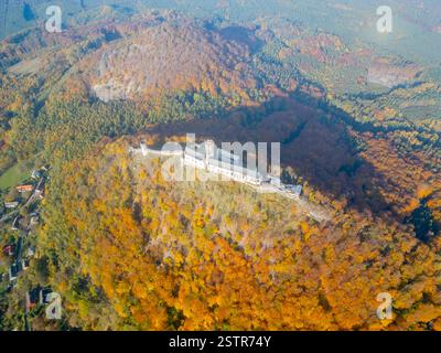 Le château médiéval de Bezdez se dresse majestueusement au sommet d'une colline, embrassé par des couleurs d'automne vibrantes. La perspective aérienne met en valeur le paysage riche et l'architecture historique dans cette vue panoramique. Banque D'Images