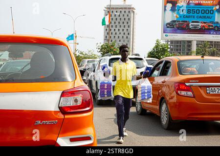 Les vendeurs de routes à Abidjan, en Côte d’Ivoire, sont l’une des entreprises risquées que les immigrants utilisent pour faire leur mode de vie en Afrique de l’Ouest. Dissiper le danger Banque D'Images