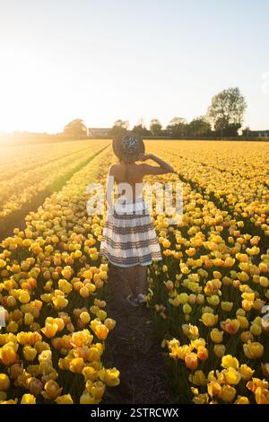 Belle femme avec robe libre de dos et marchant dans un champ de fleurs dans la région des bulbes près de lisse aux pays-Bas. Banque D'Images