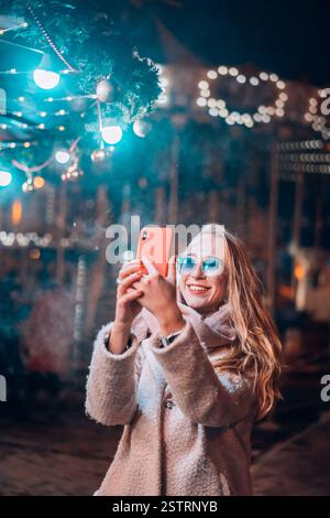 Femme prend sur fond flou artistique en selfies en lumière le soir de la rue Banque D'Images