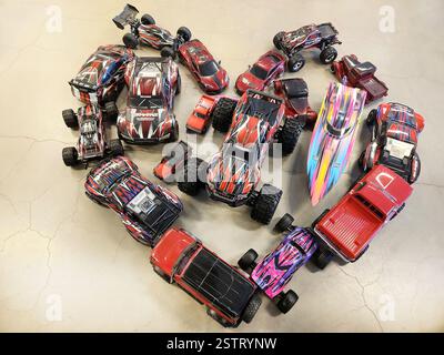 Voitures Traxxas télécommandées et bateau disposés en forme de coeur sur plancher de béton. Suède. Banque D'Images