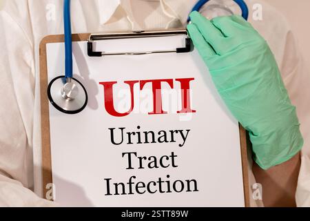 Concept d'UTI - infection des voies urinaires écrire sur la paperasse avec stéthoscope isolé sur fond de bois. Banque D'Images